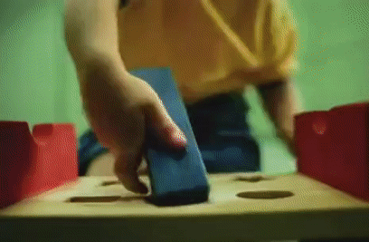'A child trying and failing to use a hammer to bash a shape into a shape sorter toy'